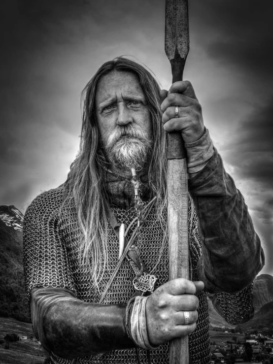 a viking with a scab beard is holding an ax in front of the camera