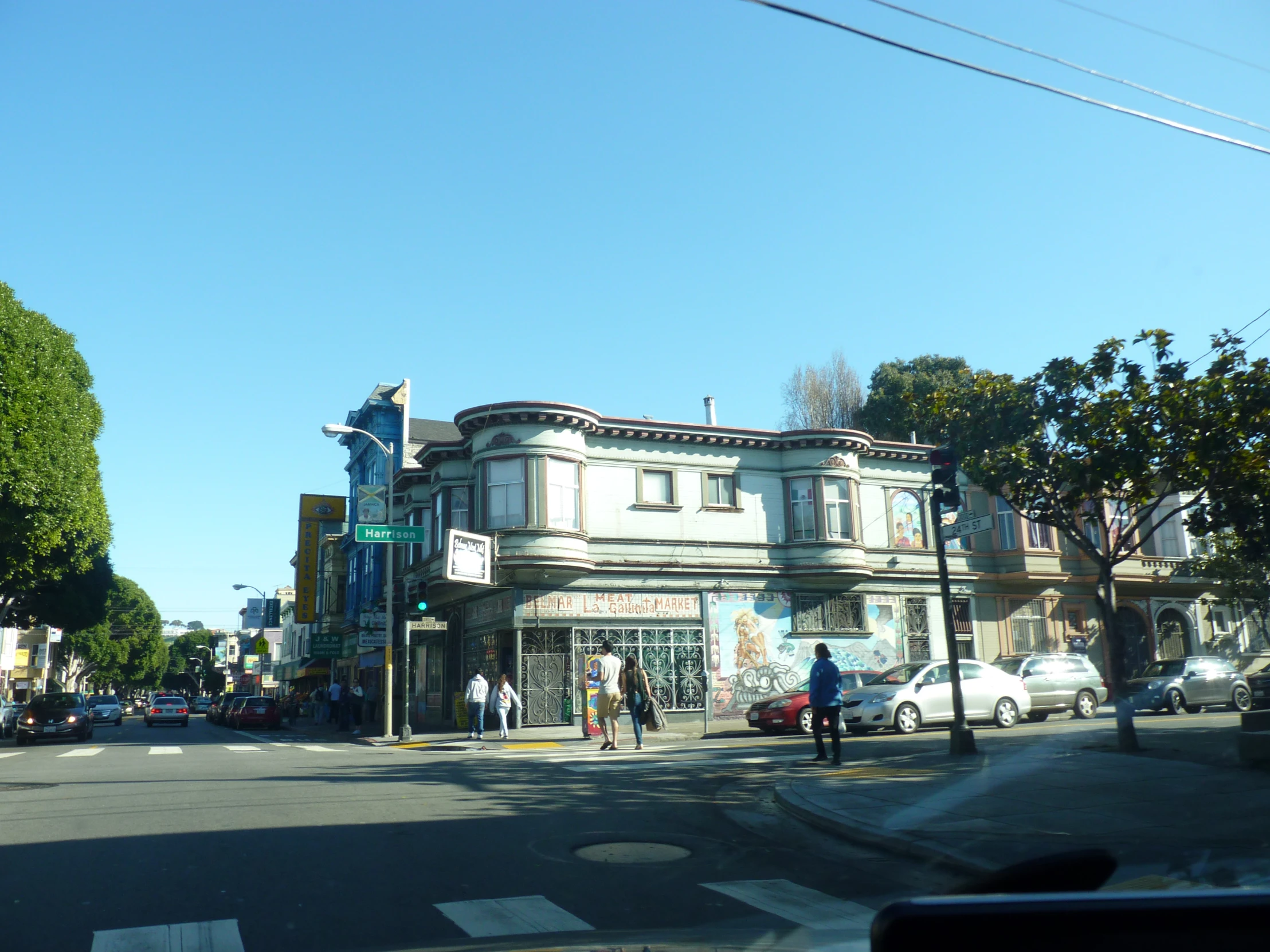 the corner of a street that shows cars, people and buildings