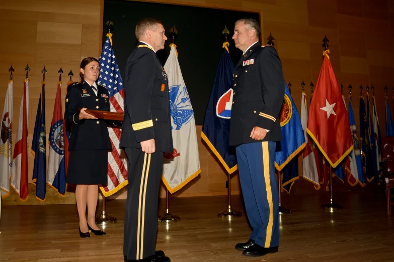 two military officers standing in front of flags