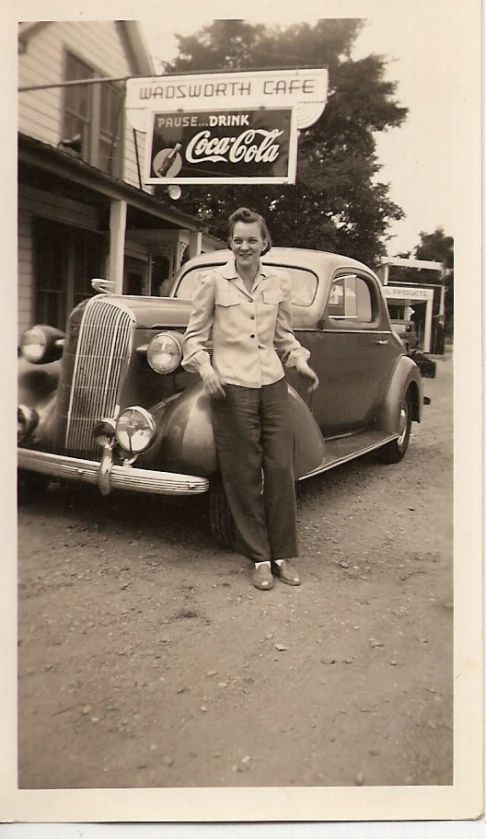 a vintage po shows a man standing next to his old car