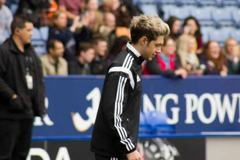 a man with blonde hair stands in front of a crowd