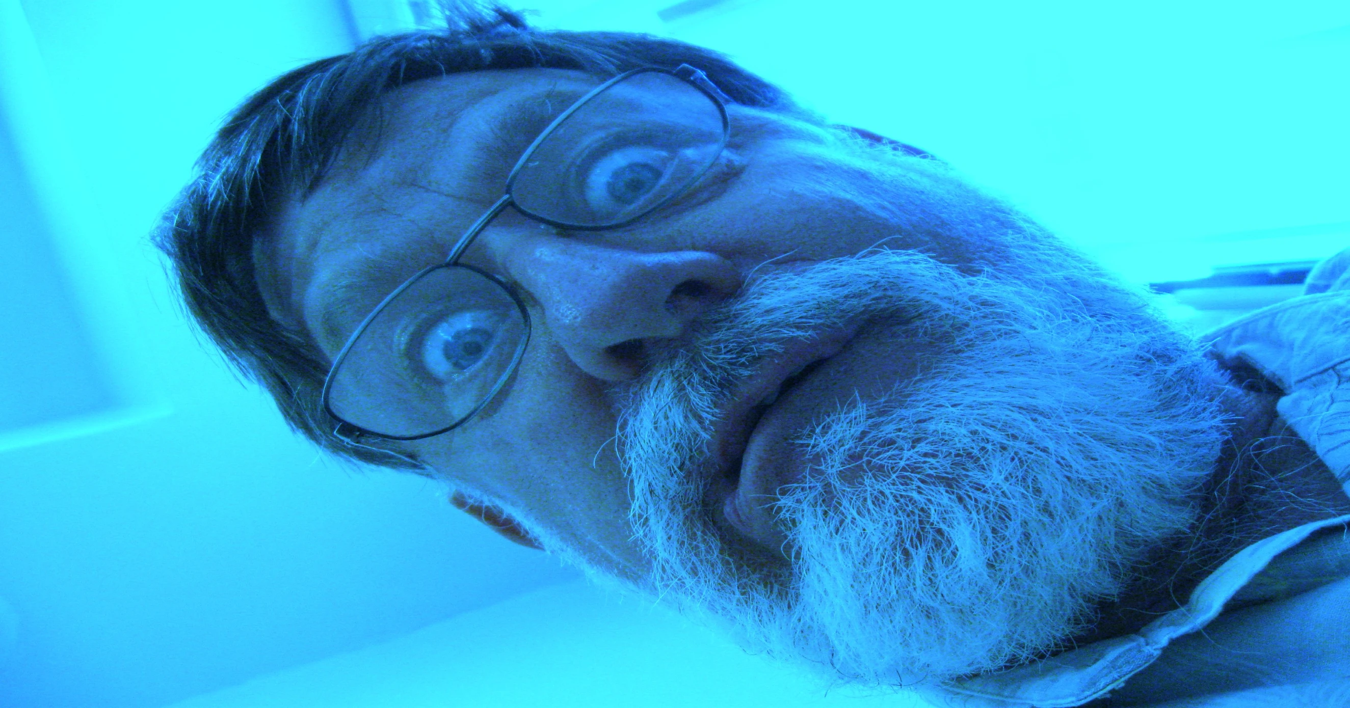 a man with glasses laying on top of a desk