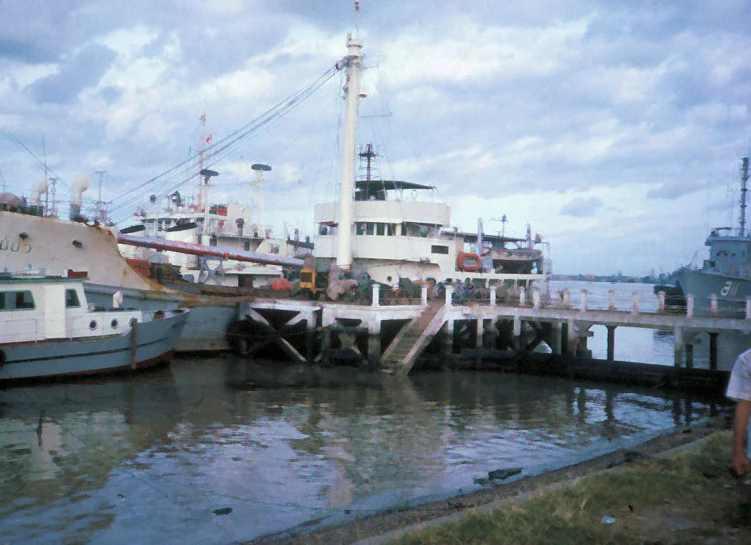 several people standing on a dock by some boats