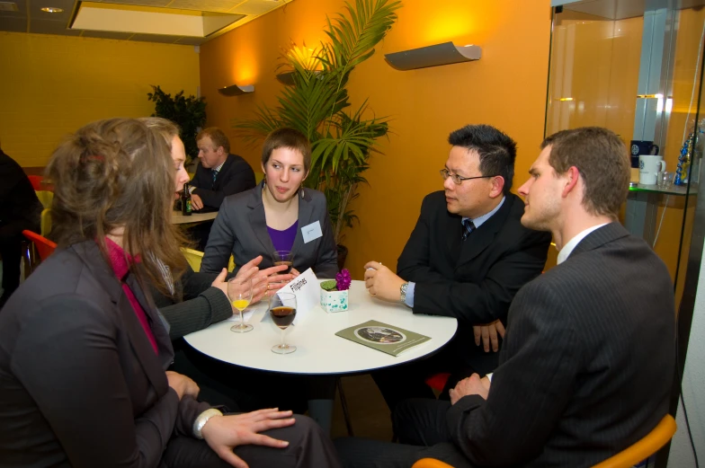 five people talking to each other at a table