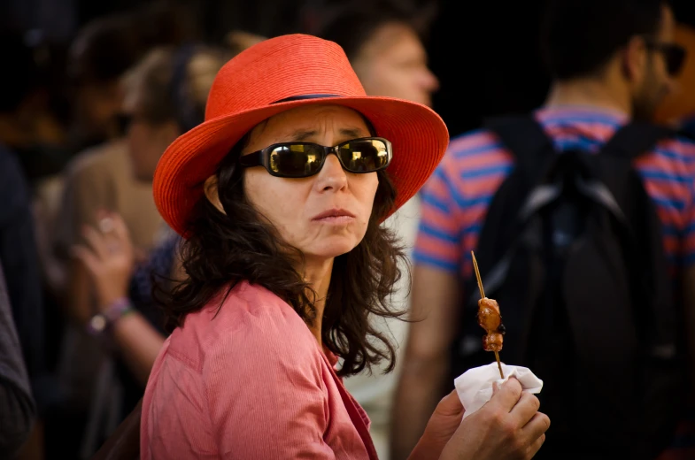 a woman wearing sunglasses and a hat is holding a  dog