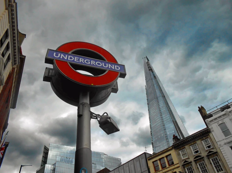 the sign for the underground train is in front of tall buildings