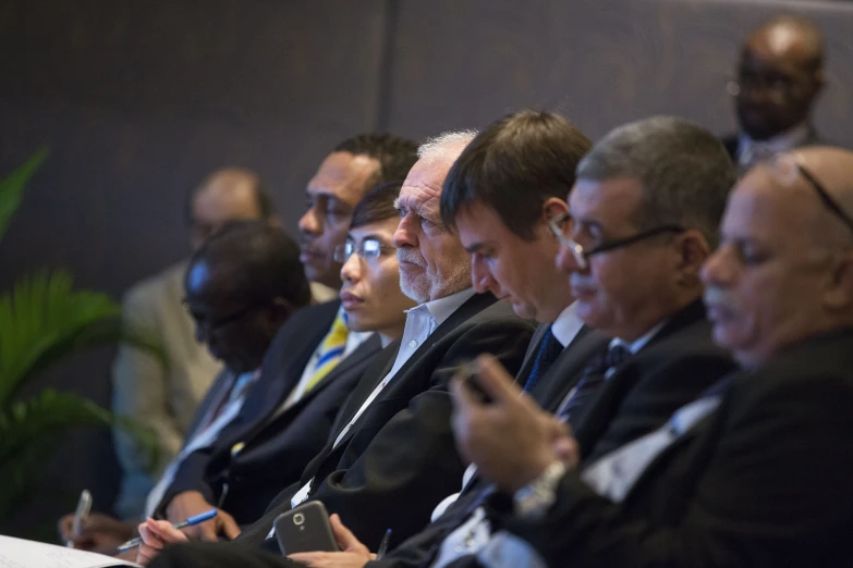 group of men sitting in a room and taking notes