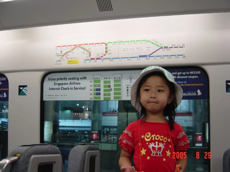 a little girl standing next to some seats in a train
