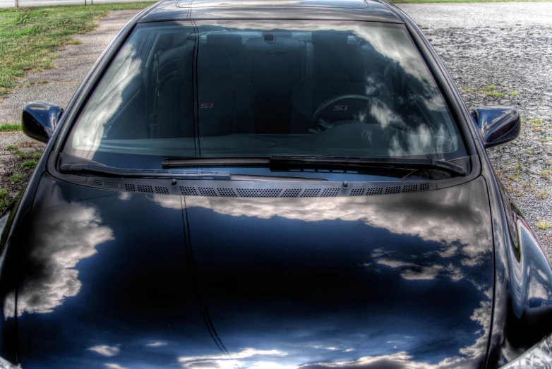 the hood and windows of a car reflecting clouds
