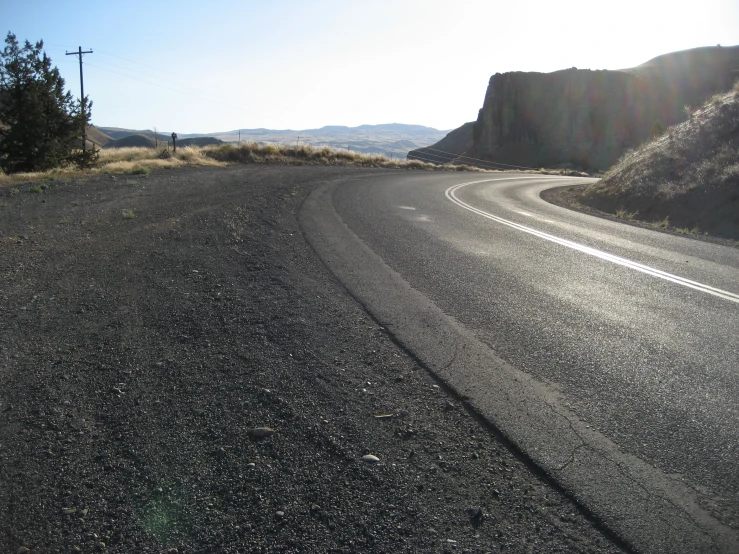 an empty winding road with mountains in the distance