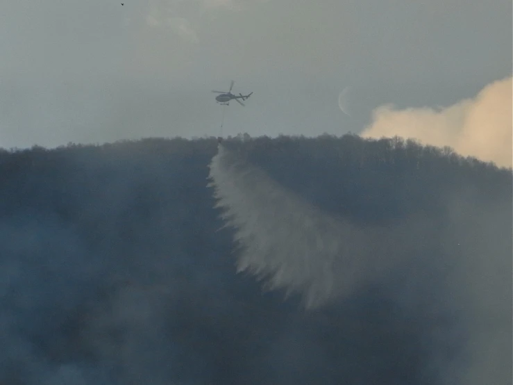 a helicopter flying low over a forested area