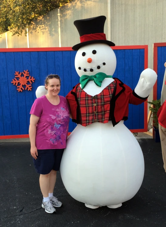 a woman standing next to a large inflatable snowman