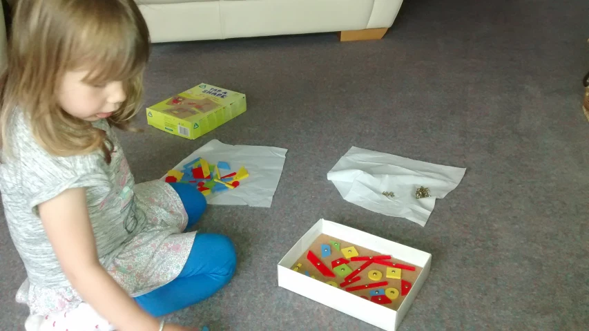 there is a girl sitting on the floor playing with toy