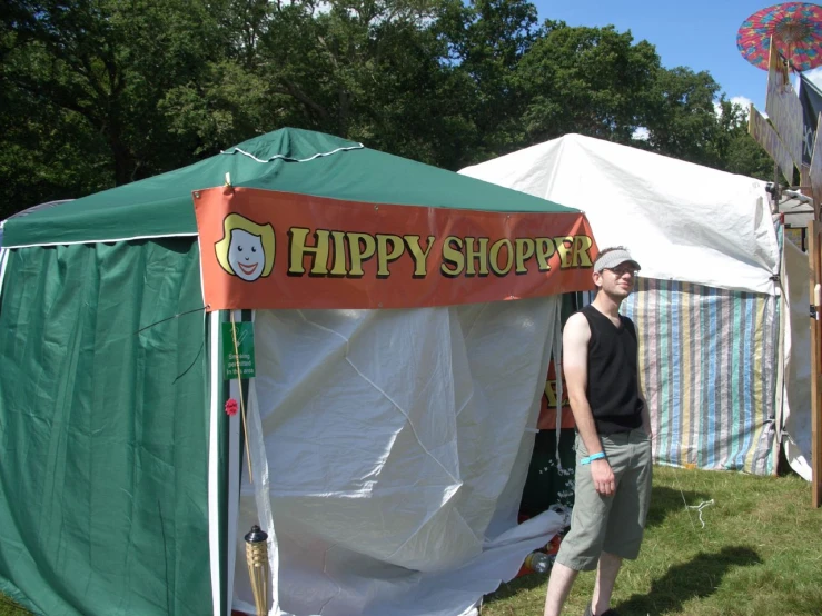 the man stands underneath a colorful happy shoppe tent