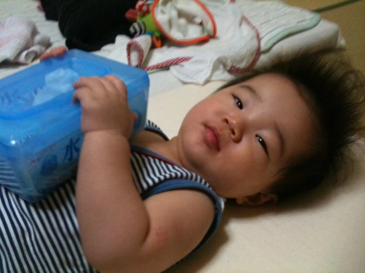 the baby is laying down and smiling with his blue container