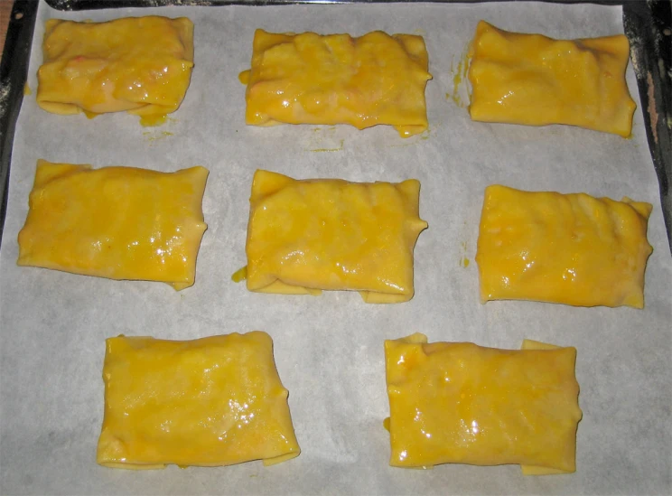 yellow pastry dough is rolled up and laying on paper