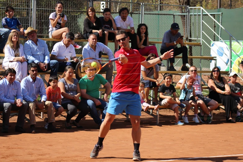 a man hitting a tennis ball while people watch