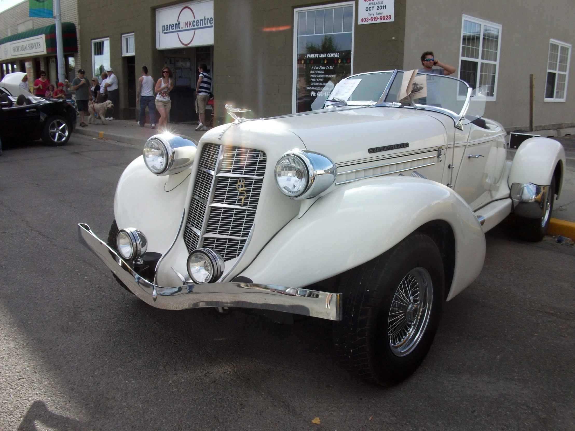 an antique car sits parked in front of a business