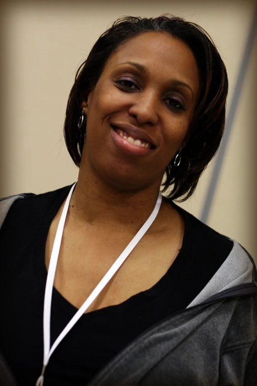 a woman smiling at the camera while wearing a pendant