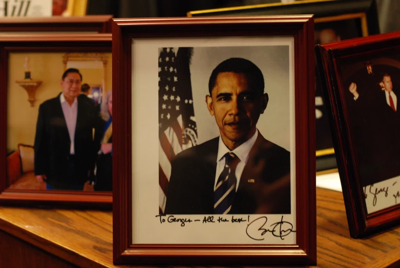 three pictures of barack obama in a brown wood frame and one with a signed picture of his father and the president