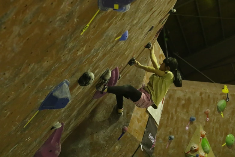 a woman climbs a rock wall on an indoor climbing surface