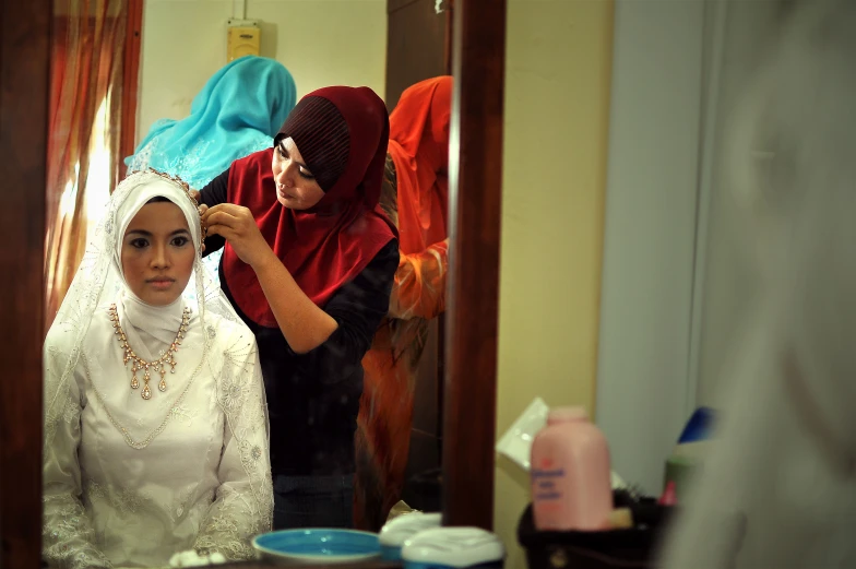 a woman getting her hair done in the mirror