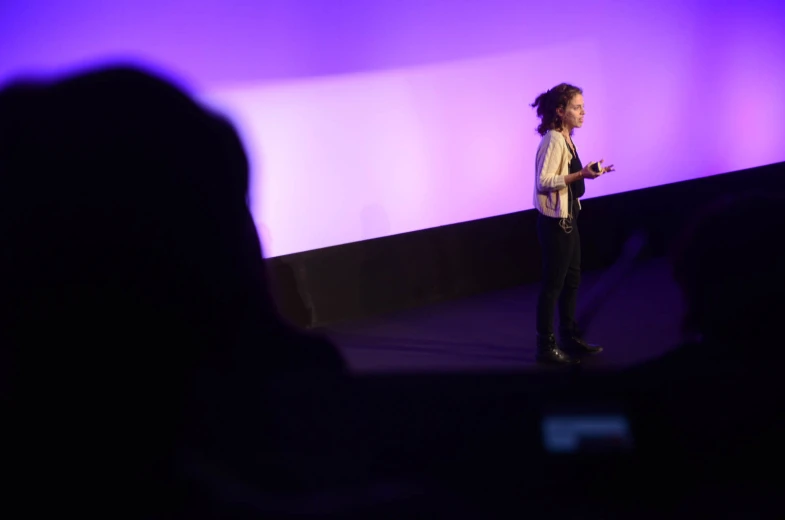 a woman talking at a stage next to people