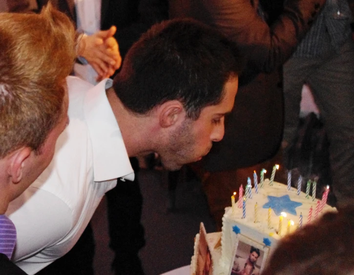 a man blowing out birthday candles on a cake