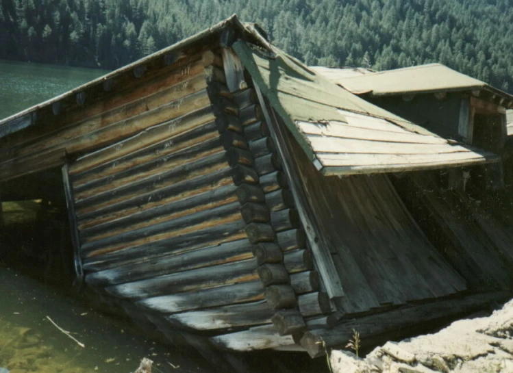 an old log cabin sitting next to a forest