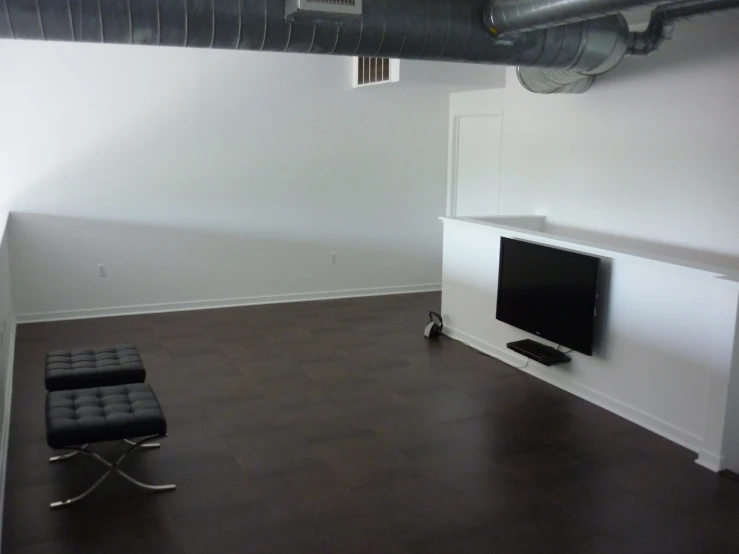 an empty room with a tv and ottoman