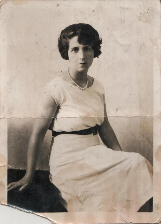 an old po of a woman sitting in front of a wall