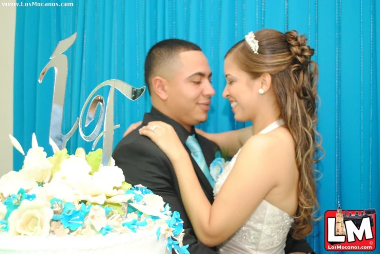 a man and woman standing next to a table holding a cake