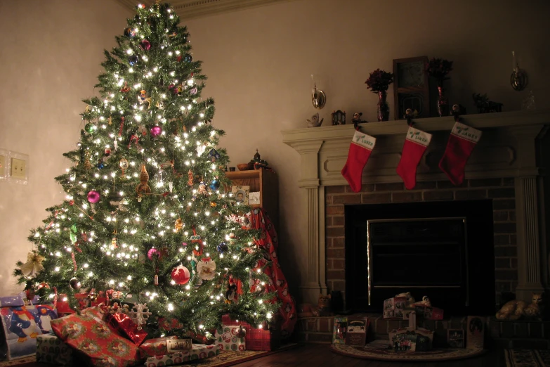 the decorated christmas tree is in a room near the fireplace