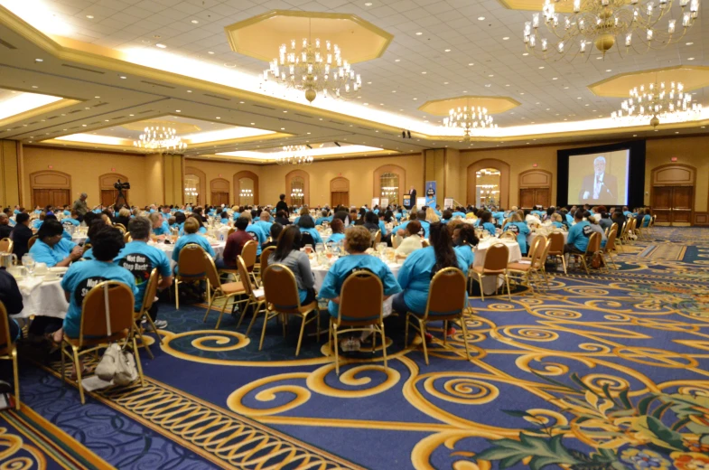 a banquet room with a crowd of people sitting around the tables