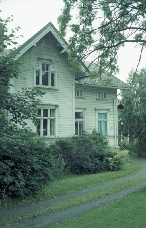 an old white wooden house with a pathway leading to it