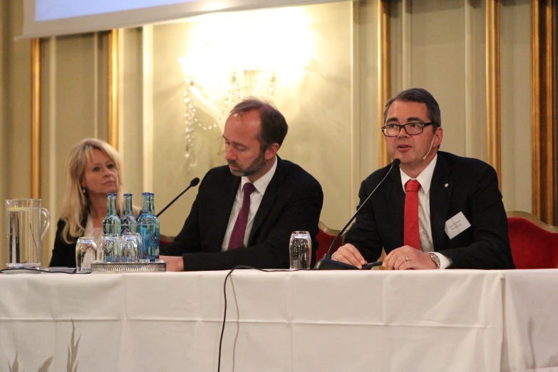 two men and a woman are sitting in front of microphones