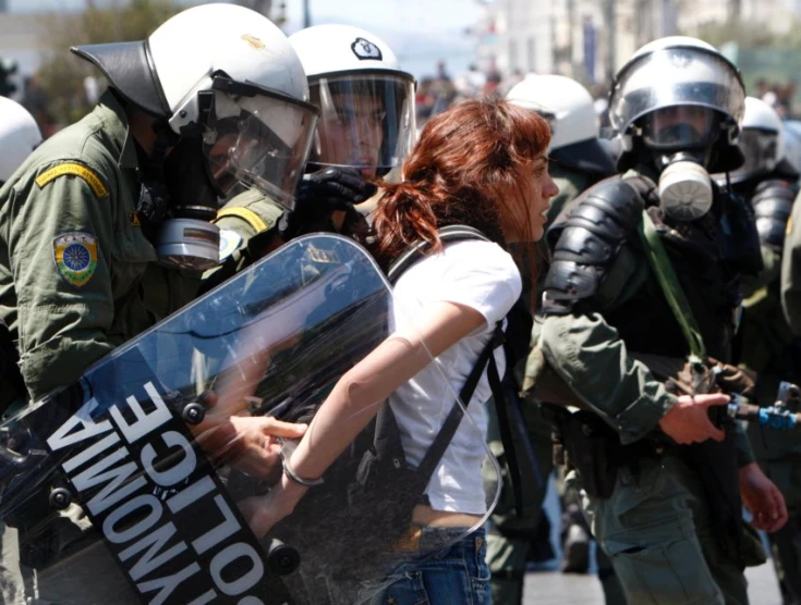 woman in white t - shirt with police standing behind her