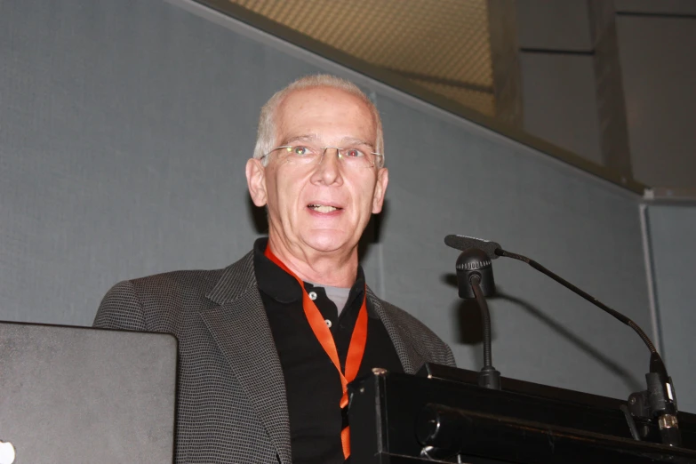 a man standing behind a microphone and giving a speech