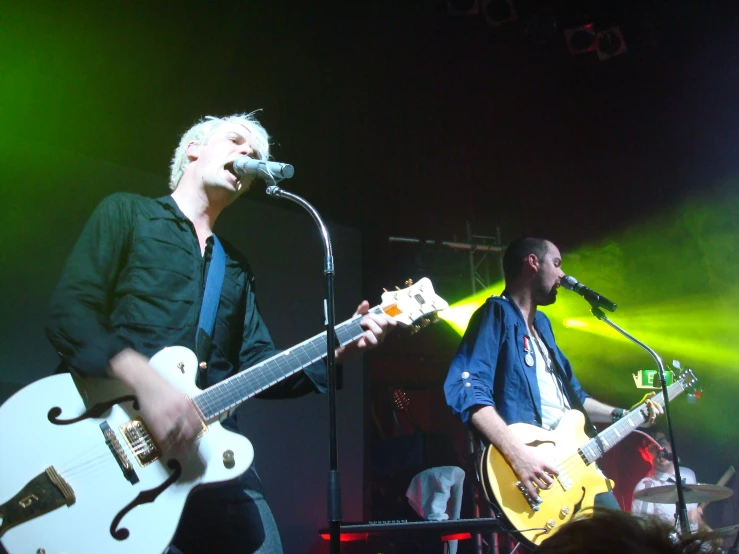 two male musicians are singing with guitars and playing keyboards