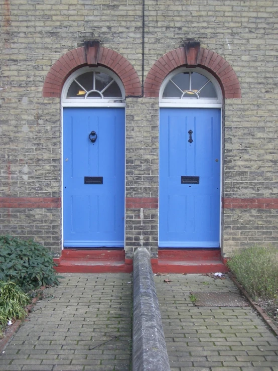 two blue double doors in front of a brick building