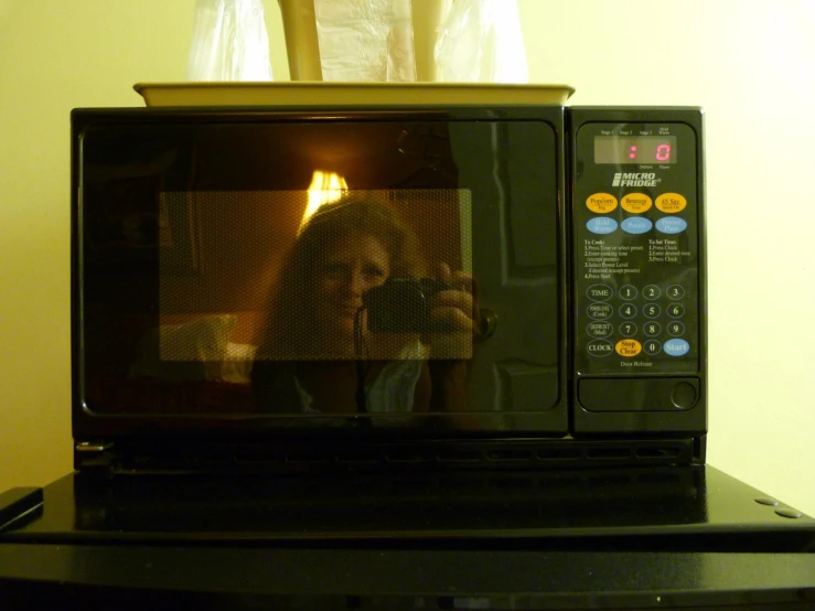 a person holding up a cell phone in a microwave