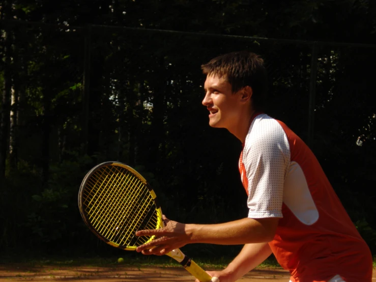 young man holding a tennis racket getting ready to serve