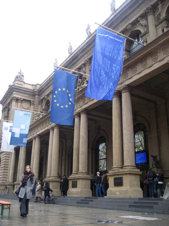 two flags hanging from poles near some pillars