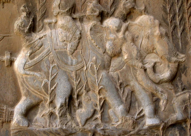 bas relief on wall showing two men playing with two elephants