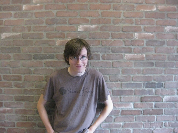 a man standing in front of a brick wall