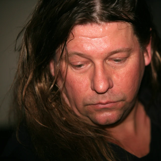 a man with long hair has his eyes closed