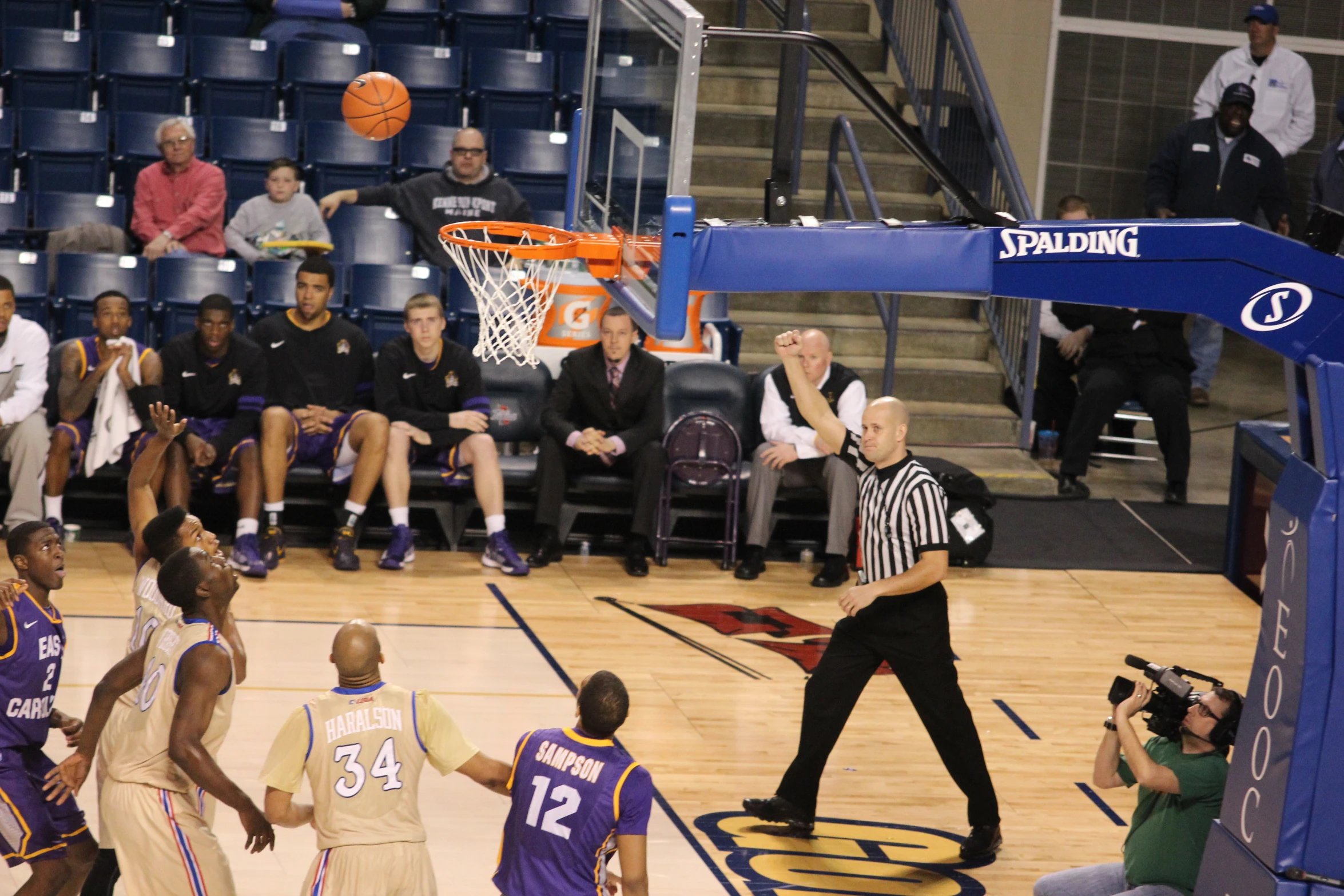 an umpire is at the basketball game while other players watch