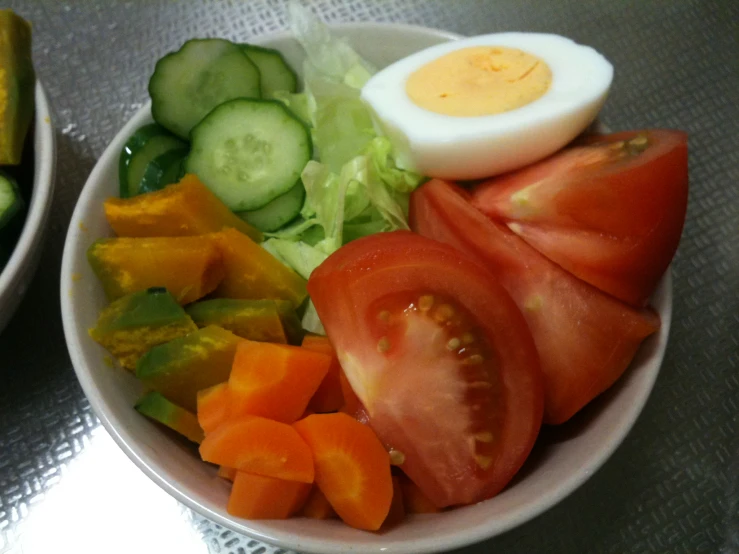 a close up of some tomatoes and vegetables in a bowl