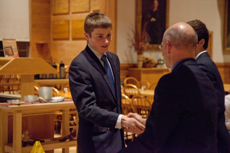 two men in suits and ties shaking hands at the reception