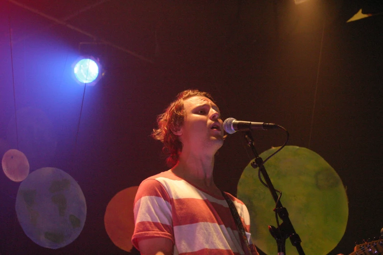 a woman singing on a stage while holding a guitar